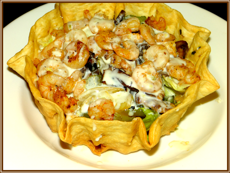 shrimp over salad in a round taco shell